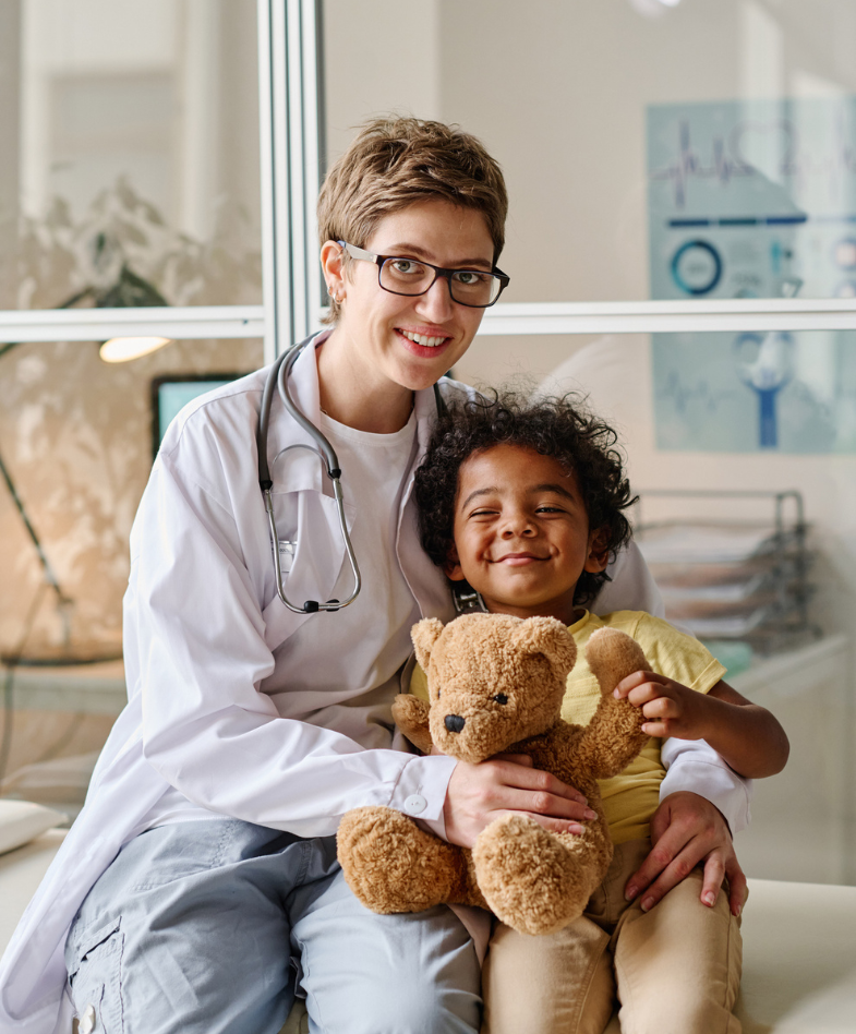 Child holding teddy sitting on hospital bed