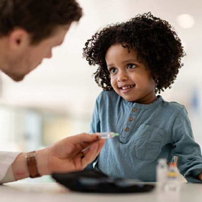 Dr. showing a needle to smiling black girl 