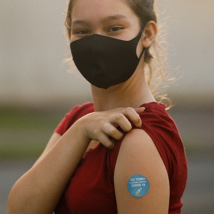 Masked youth showing bandaid over vaccine site