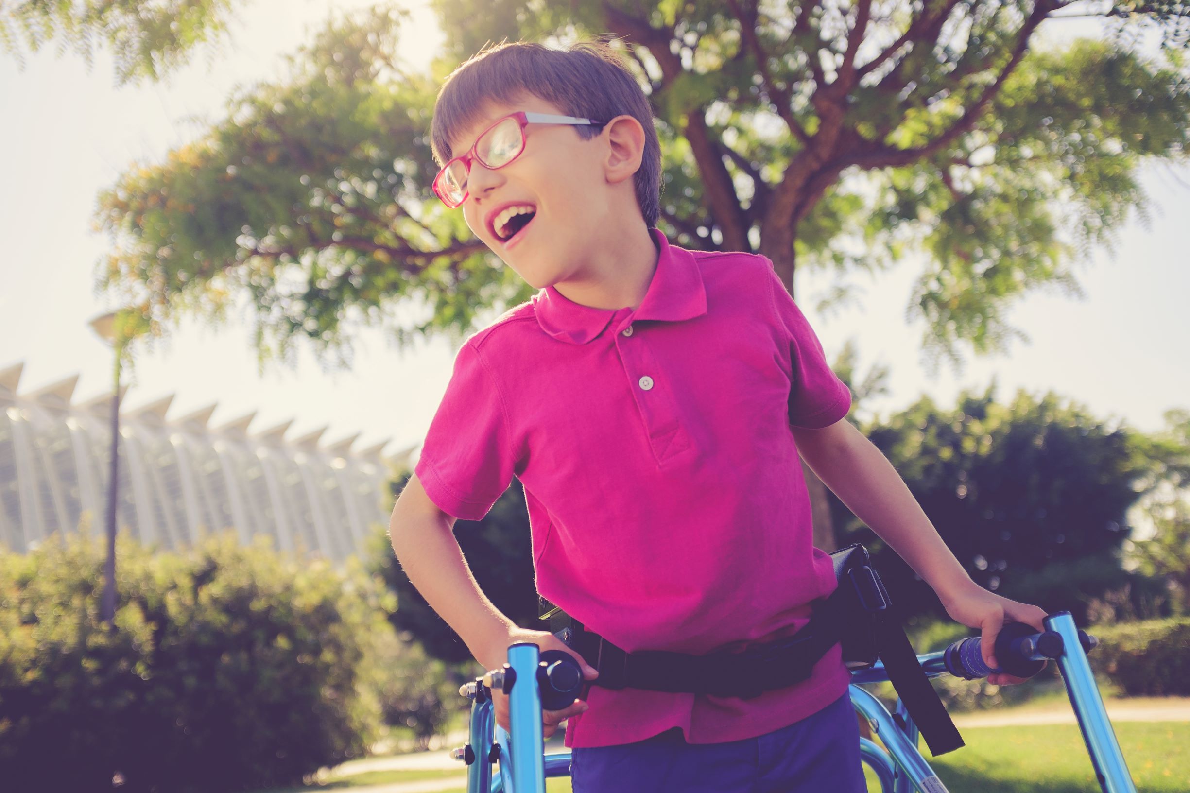 Young boy in pink shirt using walker 