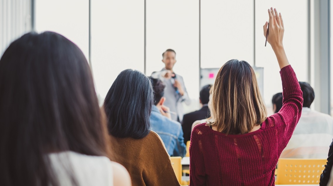 person with hand up in a classroom setting