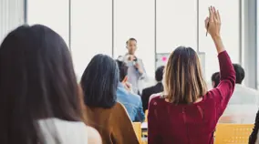 person with hand up in a classroom setting