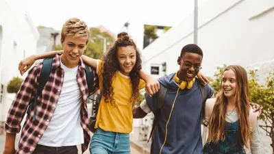 A group of youth walking with their arms draped over each others shoulders